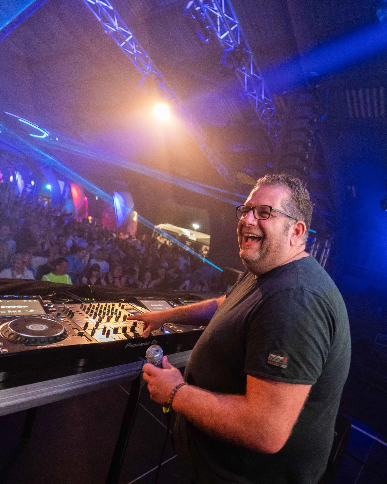 Basti van den Sroeden am DJ Pult auf der Bühne lacht.
