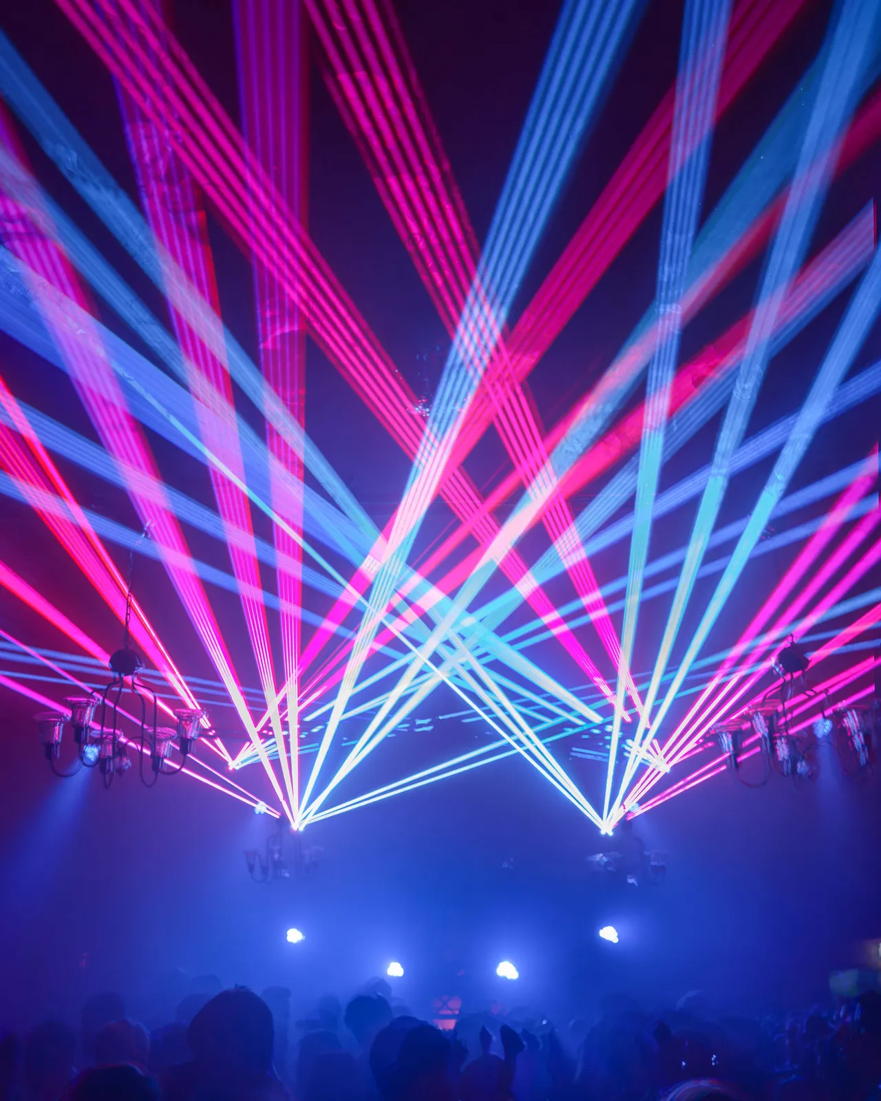 Blaue pinke Laserstrahlen bilden ein Dach über der Crowd.